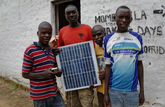 4 men holding a solar panel