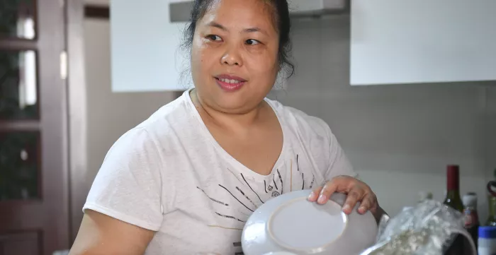 A woman domestic worker holding a dish.