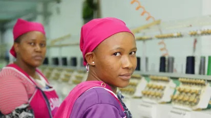 Garment workers stand next to a line of sewing machines in a clothing plant in Lesotho.